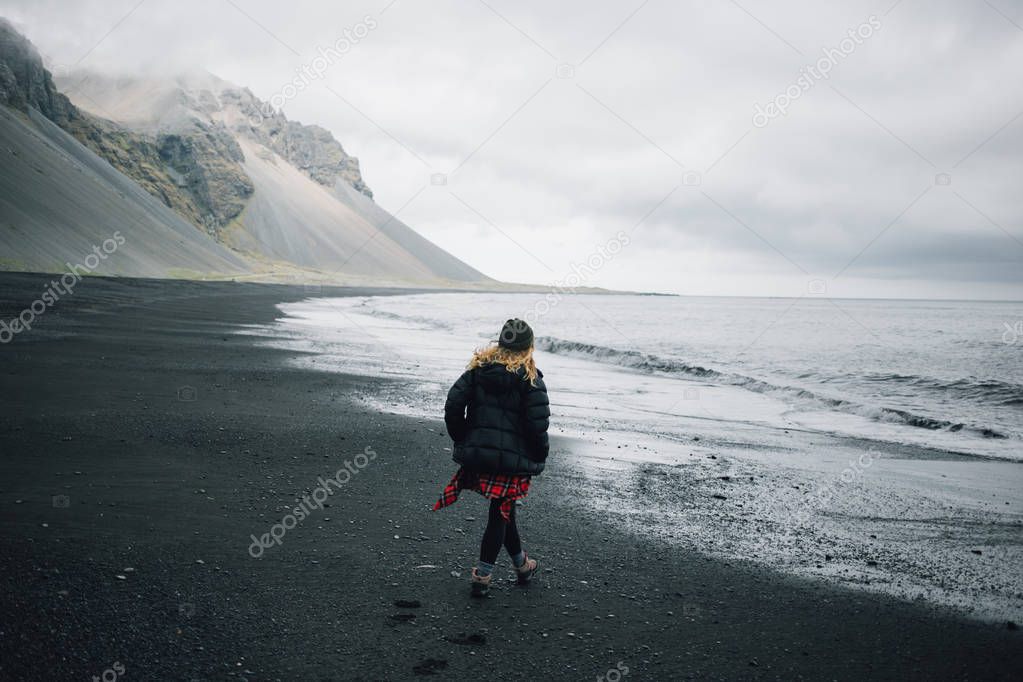 Young adventurous woman on black sand beach