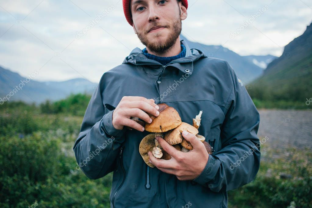 Young nomad hiker holds organic natural mushrooms