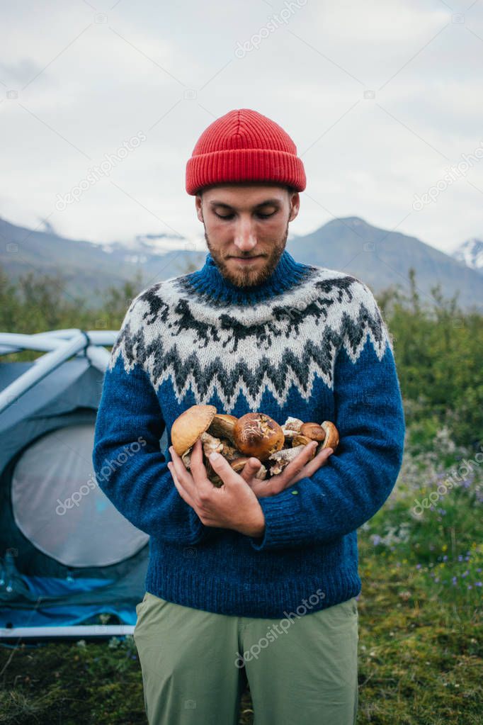 Young nomad hiker holds organic natural mushrooms