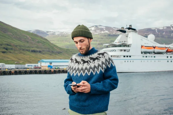 Hipster millennial man texts in fjord port — Stock Photo, Image