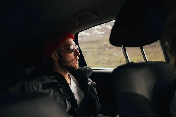 Parrakas hipsteri mies henkilöauton takapenkillä — kuvapankkivalokuva