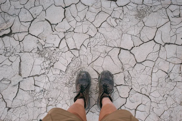 POV van wandelschoenen op droge grond bodem — Stockfoto