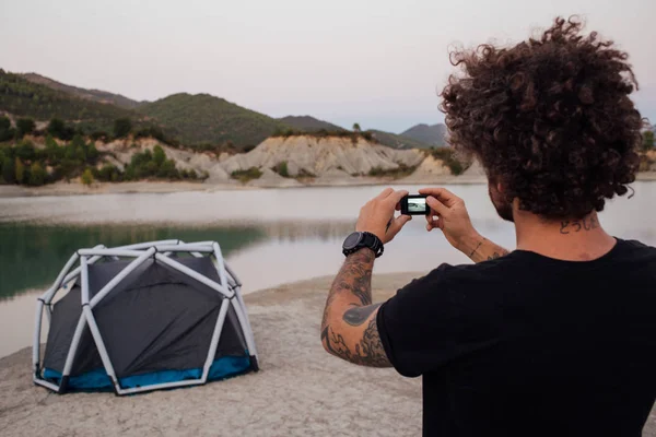 Hipster homem de viagem faz foto de tenda — Fotografia de Stock