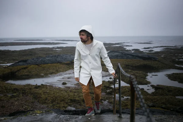 Turista en impermeable blanco camina en la orilla del hielo — Foto de Stock
