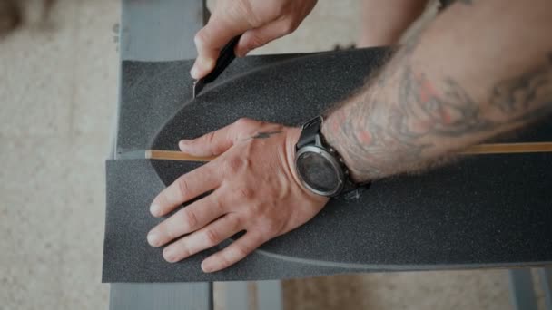 Skateboarder regrips board diy en el taller — Vídeo de stock