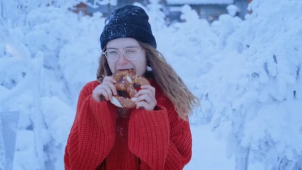 Divertido lindo adolescente come pretzel en invierno — Vídeos de Stock