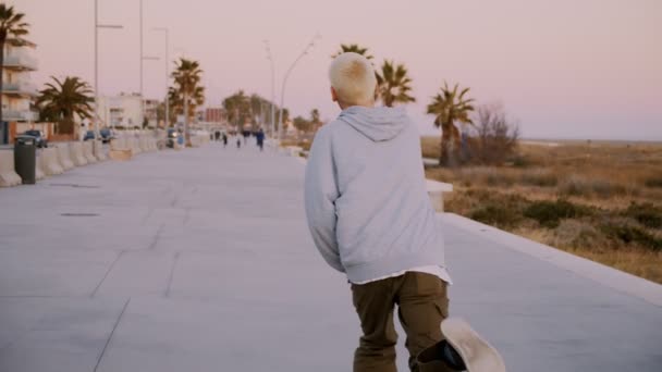 Paseos en patineta hipster Millennial en la puesta del sol — Vídeos de Stock