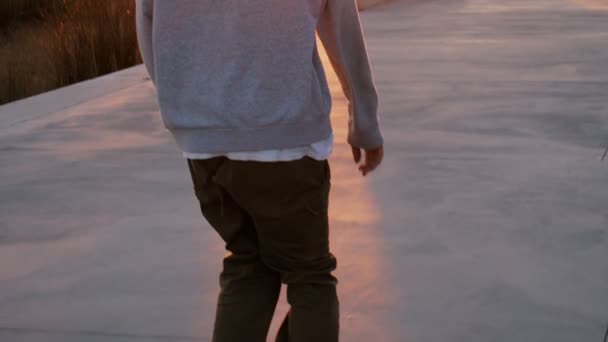 Millennial hipster skateboarder promenades au coucher du soleil — Video