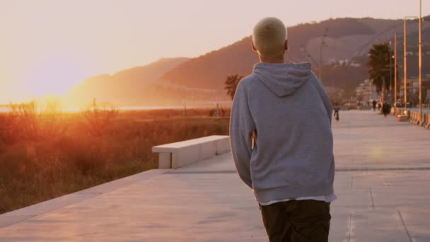 Millennial hipster skateboarder rides in sunset — Stock Video