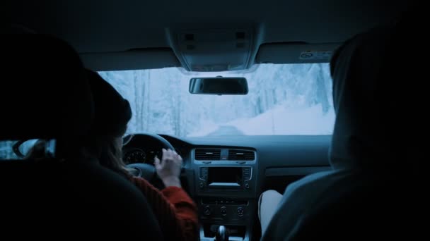 Νεαρό ζευγάρι που ταξιδεύει στο αυτοκίνητο μέσα από το δάσος του χειμώνα — Αρχείο Βίντεο
