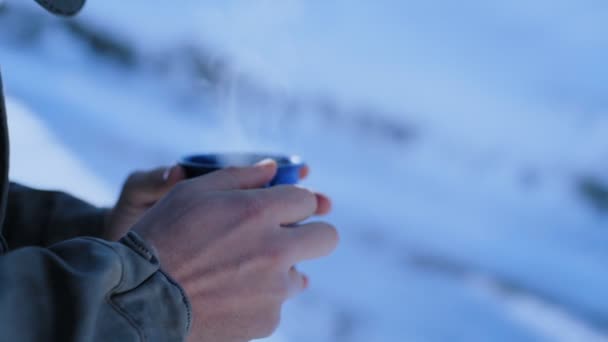 Homem detém copo de acampamento azul com vapor ao ar livre — Vídeo de Stock