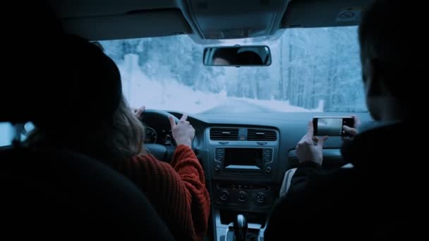 Pareja joven viaja en coche a través del bosque de invierno — Vídeos de Stock