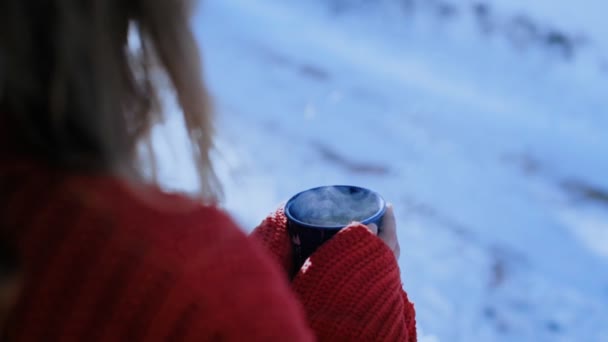 Donna in maglione rosso tiene tazza di caffè blu al di fuori — Video Stock