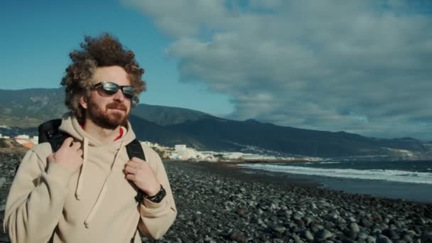 Young nomad traveller on epic mountain beach walk — Stock Video