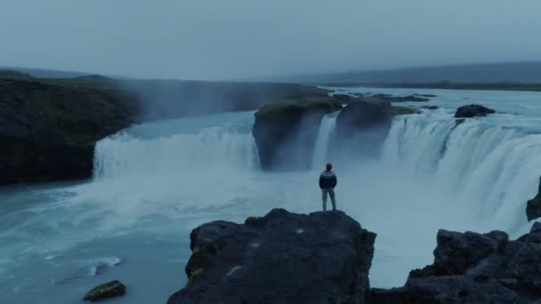 Одинокий человек на эпическом исландском водопаде Годафосс в сумерках — стоковое видео