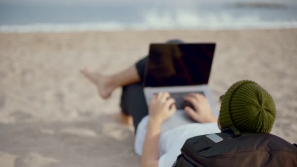 Тисячолітній кочівник працює на ноутбуці на пляжі — стокове відео