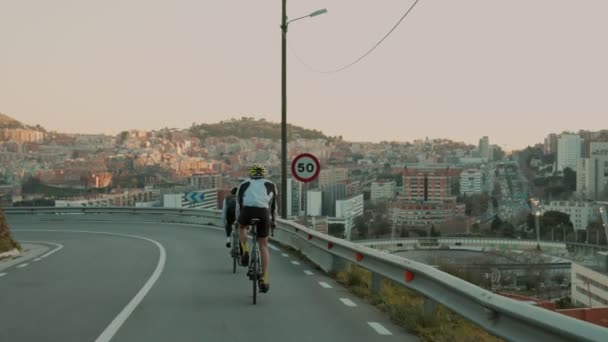 Szosowi rowerzyści jeżdżąc po zachodzie słońca górskiej drodze — Wideo stockowe