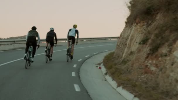 Ciclistas de carretera montando en el camino de montaña puesta de sol — Vídeos de Stock