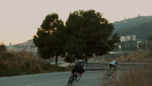 Szosowi rowerzyści jeżdżąc po zachodzie słońca górskiej drodze — Wideo stockowe