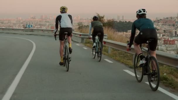 Дорожні велосипедисти катаються на гірській дорозі на заході сонця — стокове відео