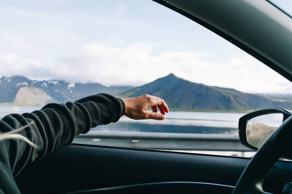 Woman holds hand out of driver window in car — Stock Photo, Image