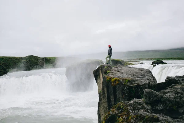 Adventurous man stand on edge of cliff waterfall — Stock Photo, Image