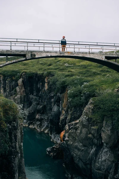 Man in outdoor kleren op hoge brug in de vallei — Stockfoto