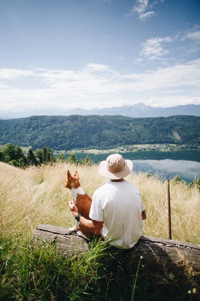 Homem de chapéu senta-se com melhor amigo cachorro cão no topo — Fotografia de Stock