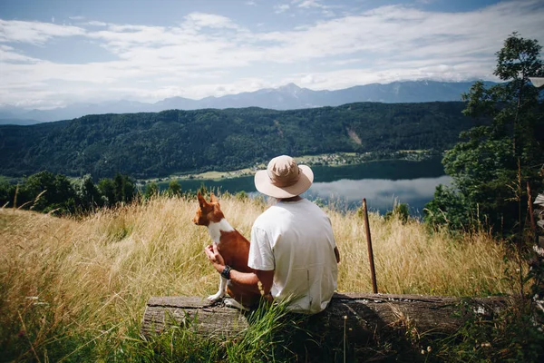 Homem de chapéu senta-se com melhor amigo cachorro cão no topo — Fotografia de Stock