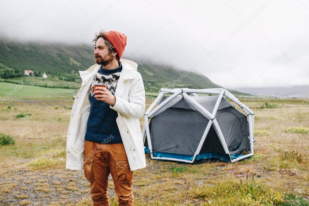 Serious rough outdoor man next to tent in iceland