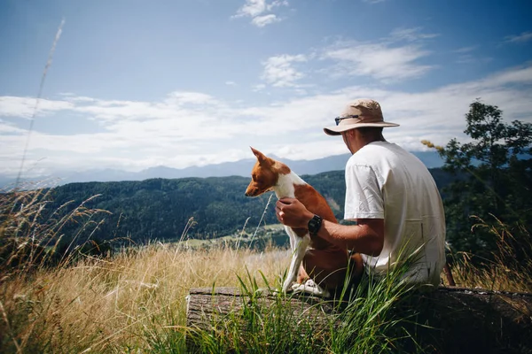 Man in hat sits with best friend dog puppy at top — Stock Photo, Image