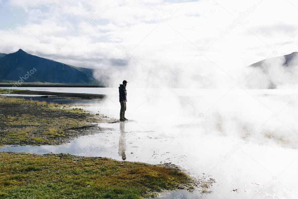 Man stand next to geiser lake and steam in iceland