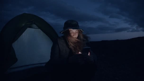 Пригоди подорожі жінка прокручує телефон на місці табору — стокове відео