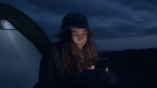 Пригоди подорожі жінка прокручує телефон на місці табору — стокове відео