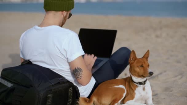 Fiatal millenniumi férfi legjobb barátja kutya a strandon — Stock videók