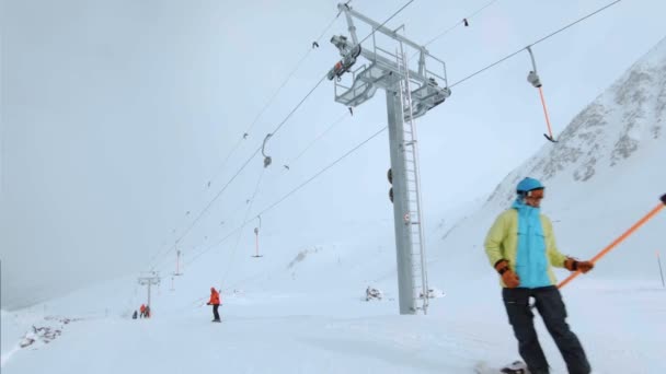 Snowboardfahrer am Schlepplift winkt Hallo — Stockvideo
