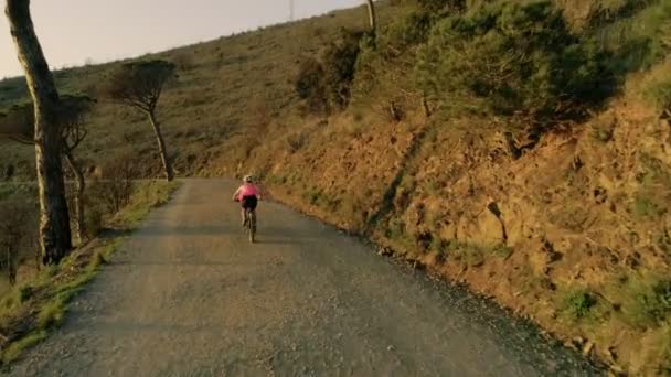 在日落骑自行车的妇女的无人机镜头 — 图库视频影像