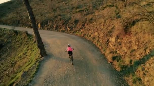 Imágenes de drones de una ciclista al atardecer en bicicleta — Vídeos de Stock