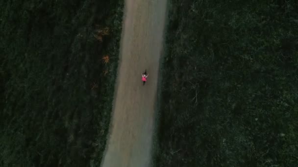Imágenes de drones de una ciclista al atardecer en bicicleta — Vídeo de stock