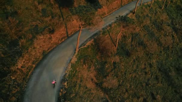 Drone footage of woman cyclist in sunset on bike — Stock Video