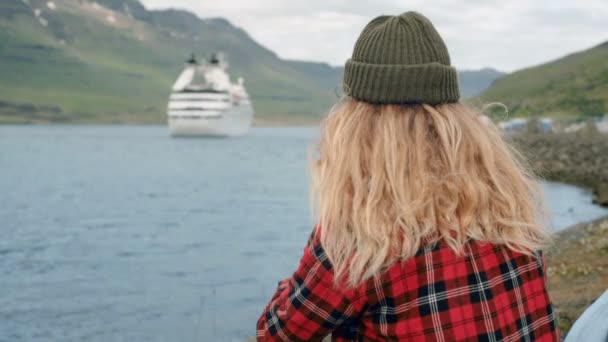 Молода жінка сидить в порту дивитися круїзний корабель відпустку — стокове відео