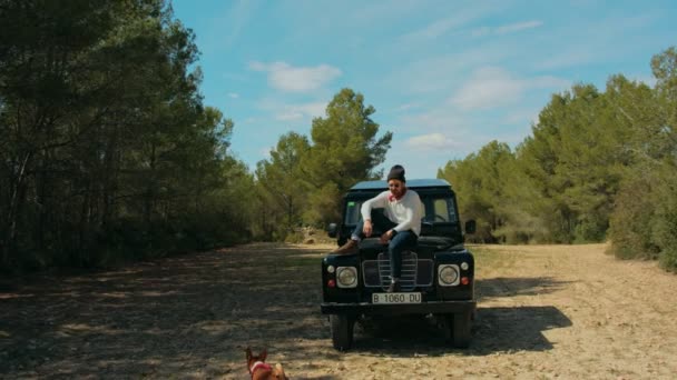 Hipster-Mann sitzt auf schwarzem Abenteuer-Jeep im Wald — Stockvideo