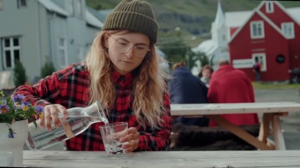 Vrouw in hipster outfit gietwater op terras — Stockvideo