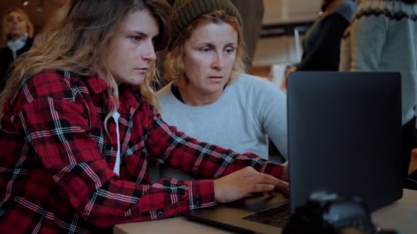 Две женщины работают на ноутбуке в кафе или коворкинге — стоковое видео