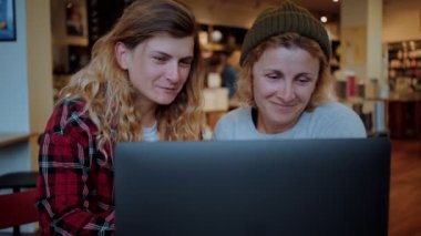 Kafede ya da birlikte çalışan iki kadın dizüstü bilgisayarda çalışıyor