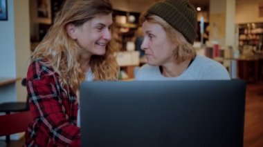 Kafede ya da birlikte çalışan iki kadın dizüstü bilgisayarda çalışıyor