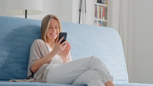 Young pretty woman use smartphone on sofa at home — Stock Video