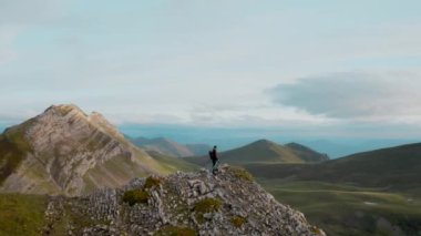Dağdaki bulutlu zirvede yürüyüşçünün drone görüntüsü
