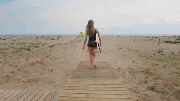 Młoda piękna kobieta z deską surfingową na plaży — Wideo stockowe