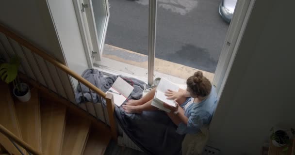 Молодая женщина в уютном пижаме пьет кофе на балконе — стоковое видео